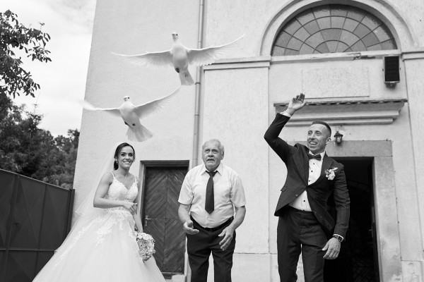 Zenich s nevestou vypustajuci holubky po obrade v kostole