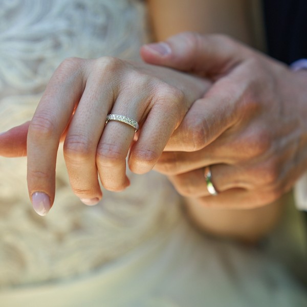 Detail ruky zenicha drziaceho ruku nevesty, zaber na prstienky