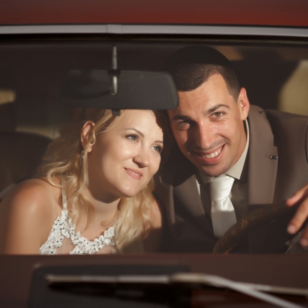 Usmievajuci sa mladomanzelia za celnym oknom svadobneho auta