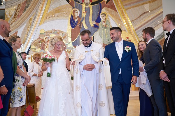 svadobny fotograf knaz vyvadza mladomanzelov z kostola po svadobnom obrade