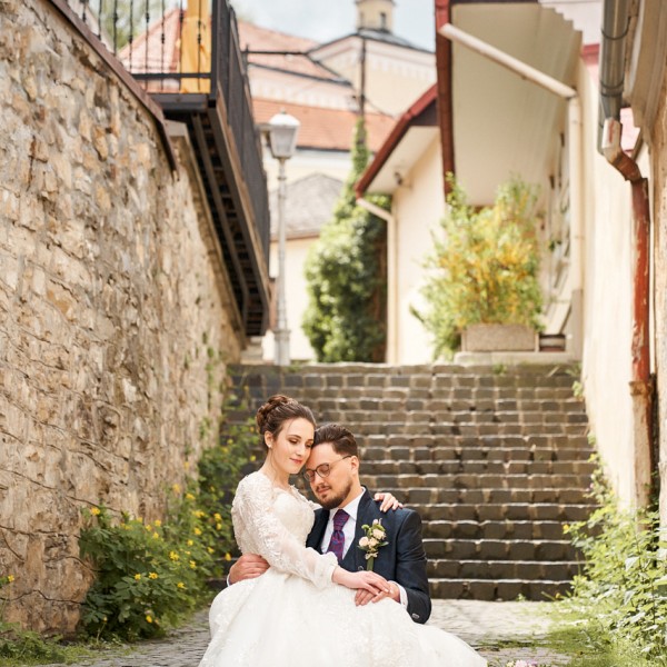 Stare ulicky Trencina, zenich sediaci na schodoch v naruci s nevestou, svadobne parove fotenie
